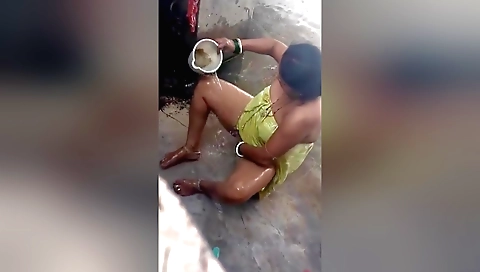 Indian milf in a nude dress and sexy dress is bathing outdoors